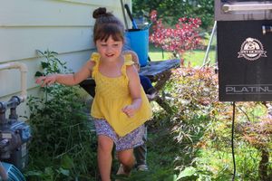 Children playing in a garden area with colorful flowers and outdoor decorations.