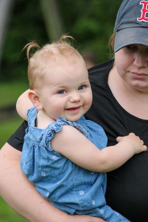 Child wearing denim outfit being held while playing outdoors.