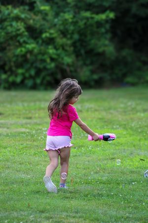 Small figure in pink chases bubbles across a grassy lawn.