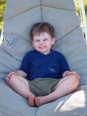 Child relaxes comfortably on white outdoor furniture cushions.