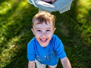 Child in bright blue shirt plays outdoors on a sunny day.