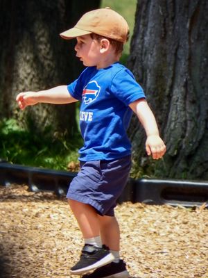 Child in blue shirt and baseball cap running and playing outdoors.