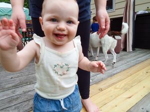 Toddler in casual clothes standing on wooden deck.