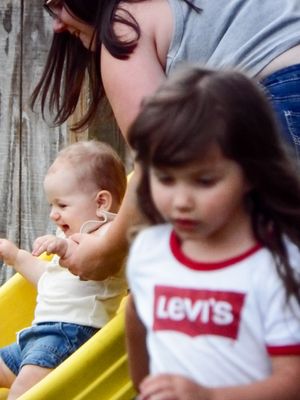 Children sitting together on yellow playground equipment.