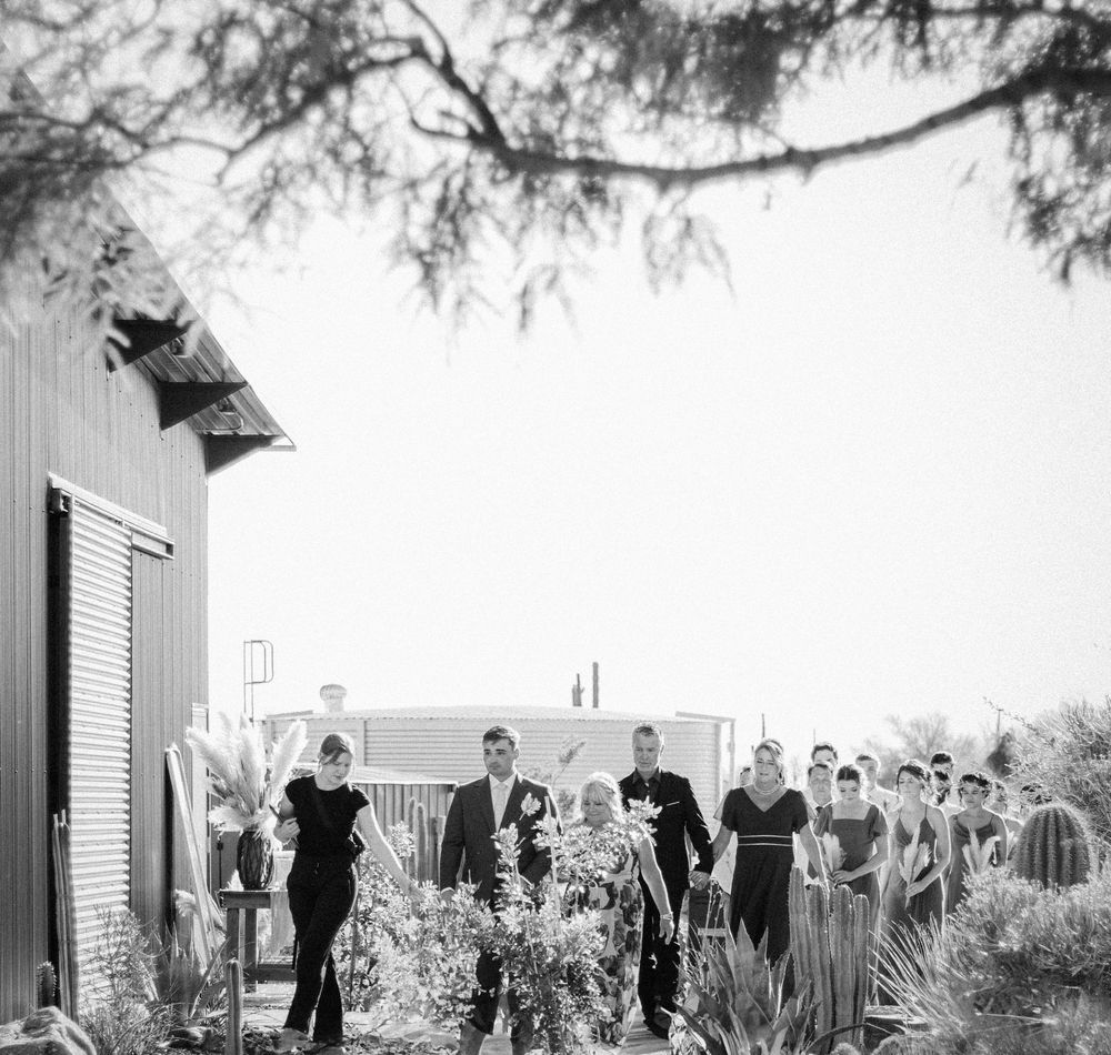 Black and white panoramic view of wedding ceremony setup with guests seated outdoors.
