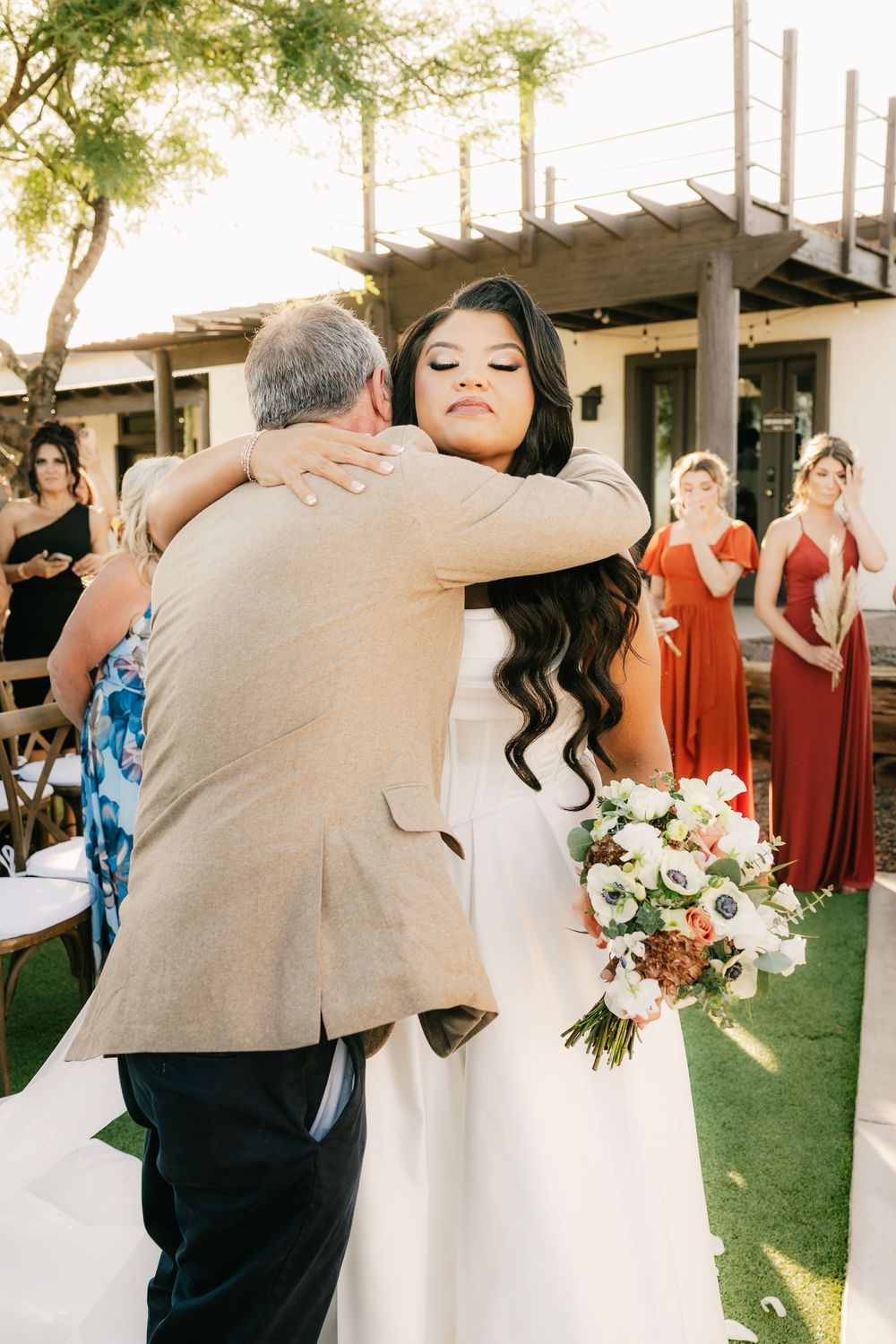 Joyful wedding celebration with bridal party in colorful dresses on lawn.