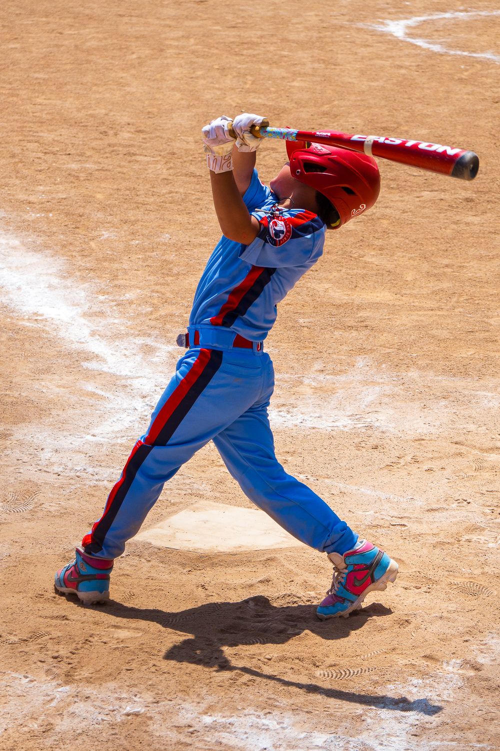Young baseball player in blue uniform demonstrates batting stance sequence on dirt field.