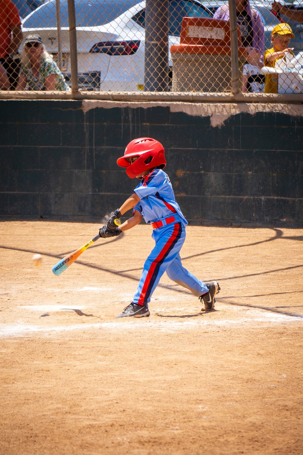 Baseball player in blue uniform demonstrates sliding technique on dirt field.