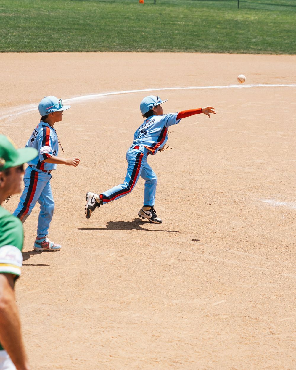 Youth baseball players practicing fielding drills on baseball diamond.