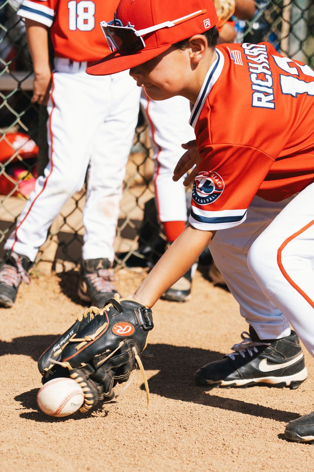Close up of baseball player's glove catching ball on dirt infield.