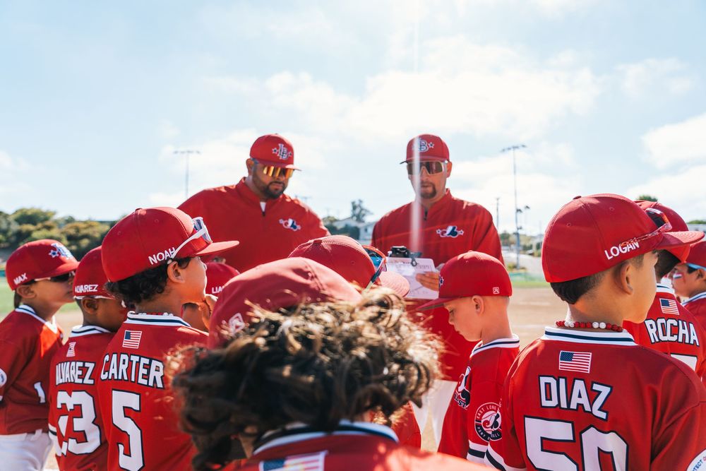 Baseball team huddle with coaches and players in red uniforms.
