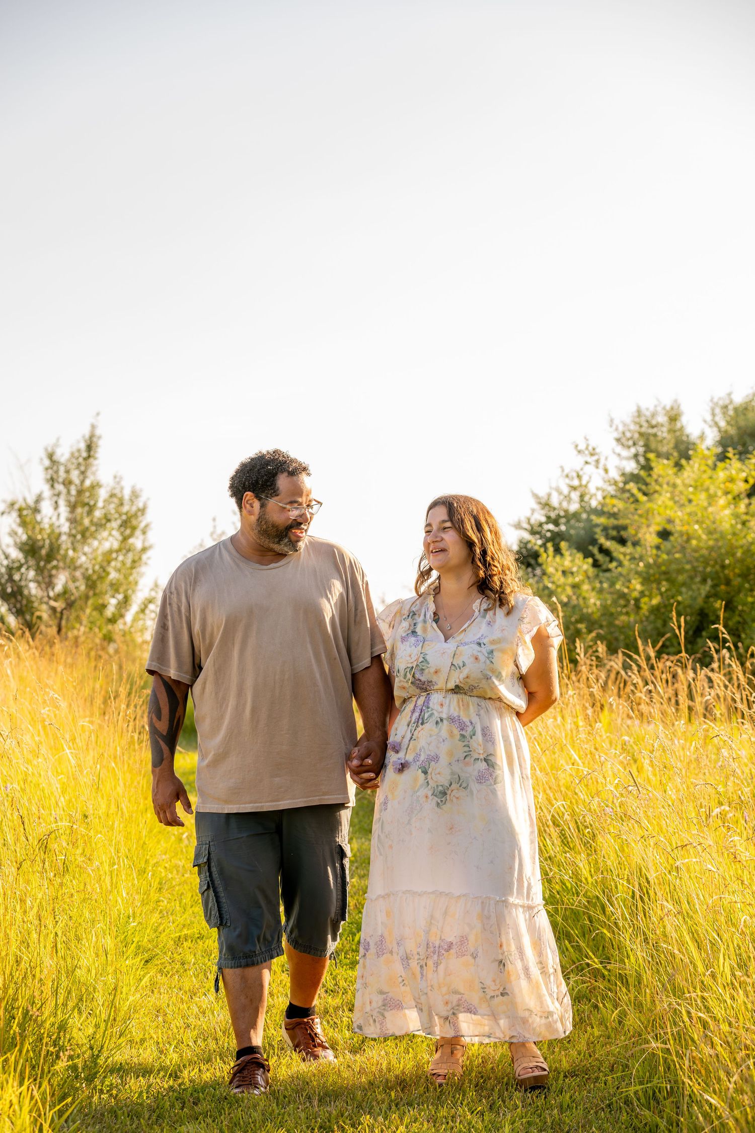 Couple enjoying a stroll through a scenic field during golden hour.