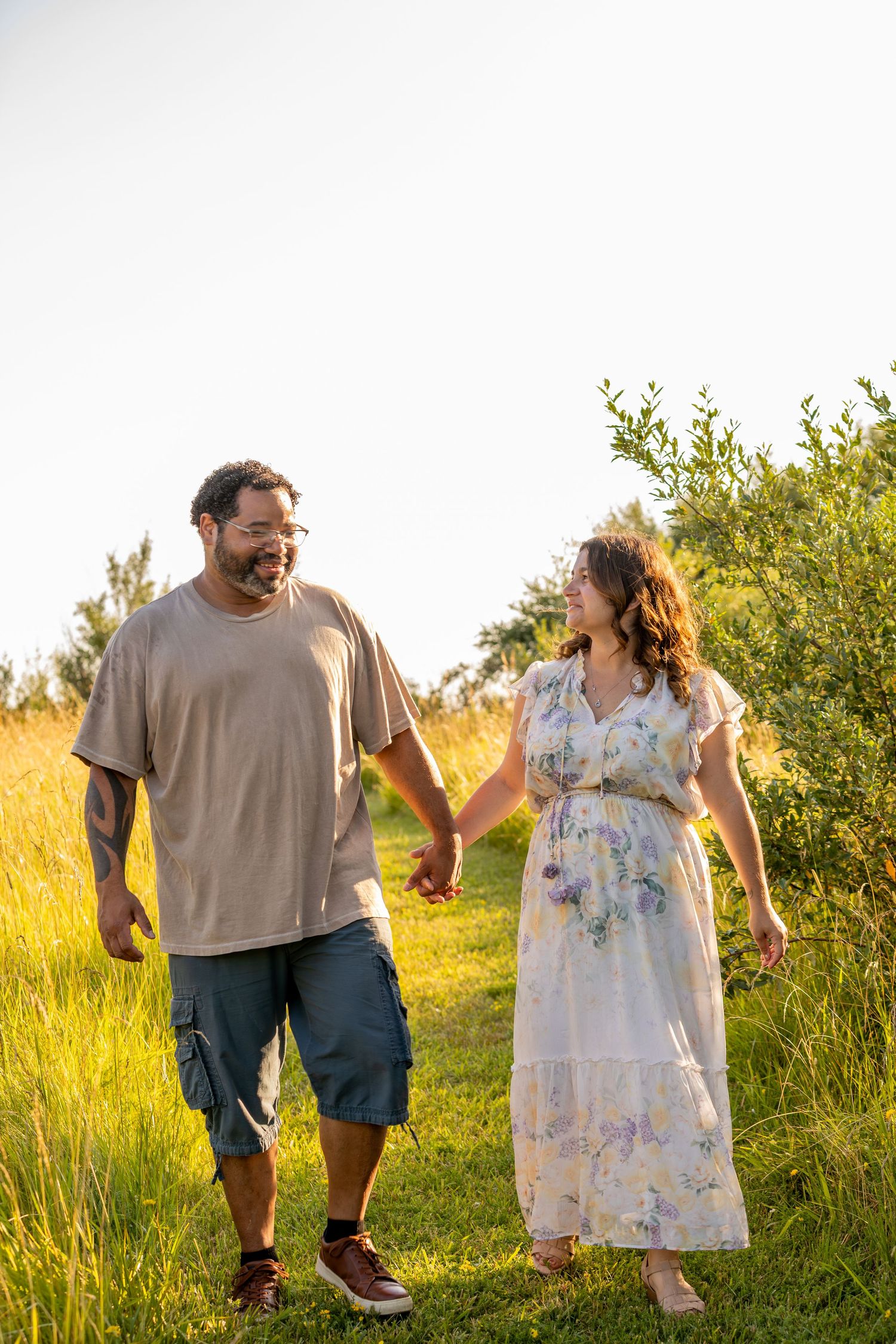 Happy couple laughing while walking through a sun-drenched meadow.