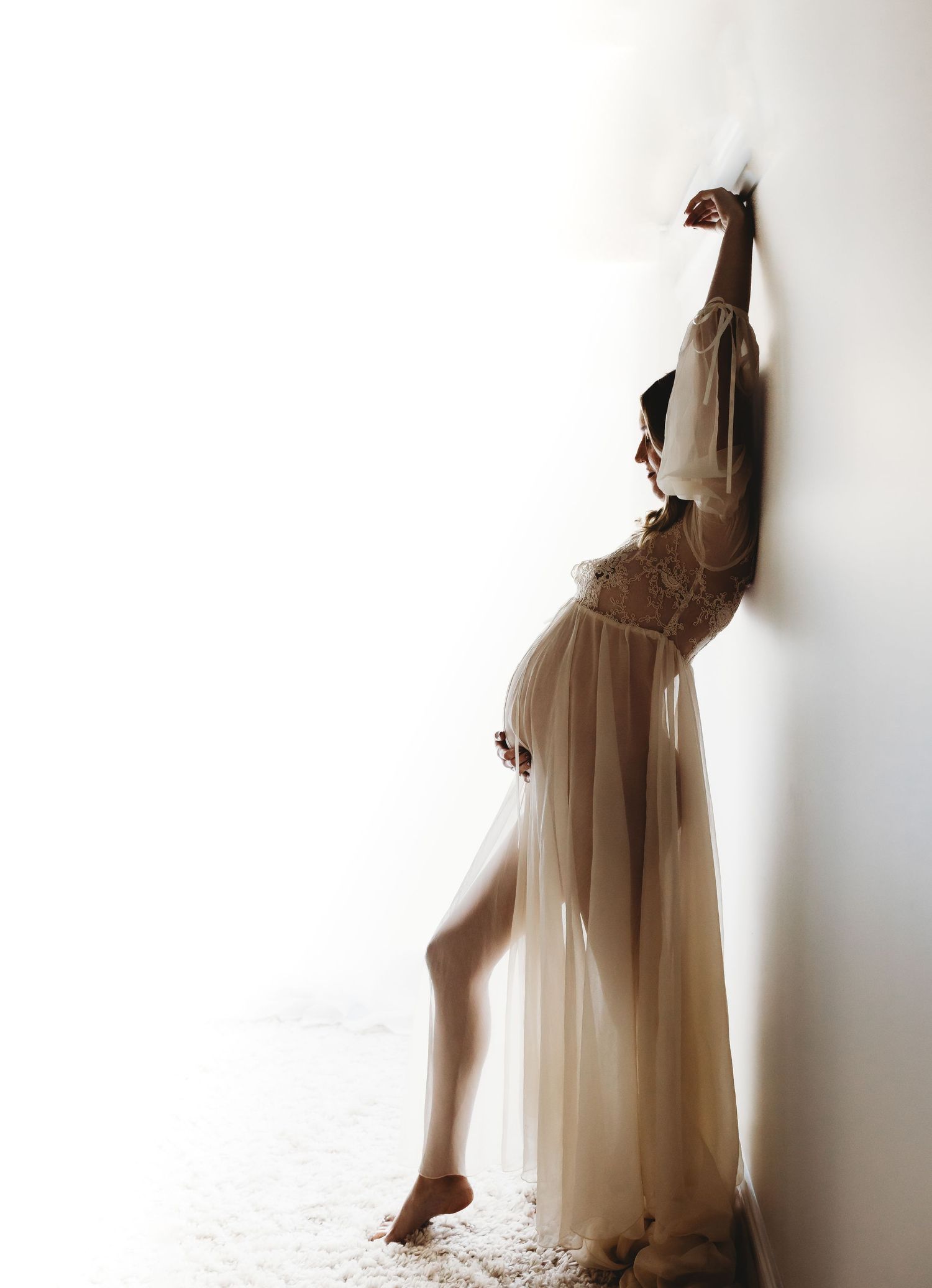 Ethereal dance poses in flowing sheer dress against white wall create artistic silhouettes.