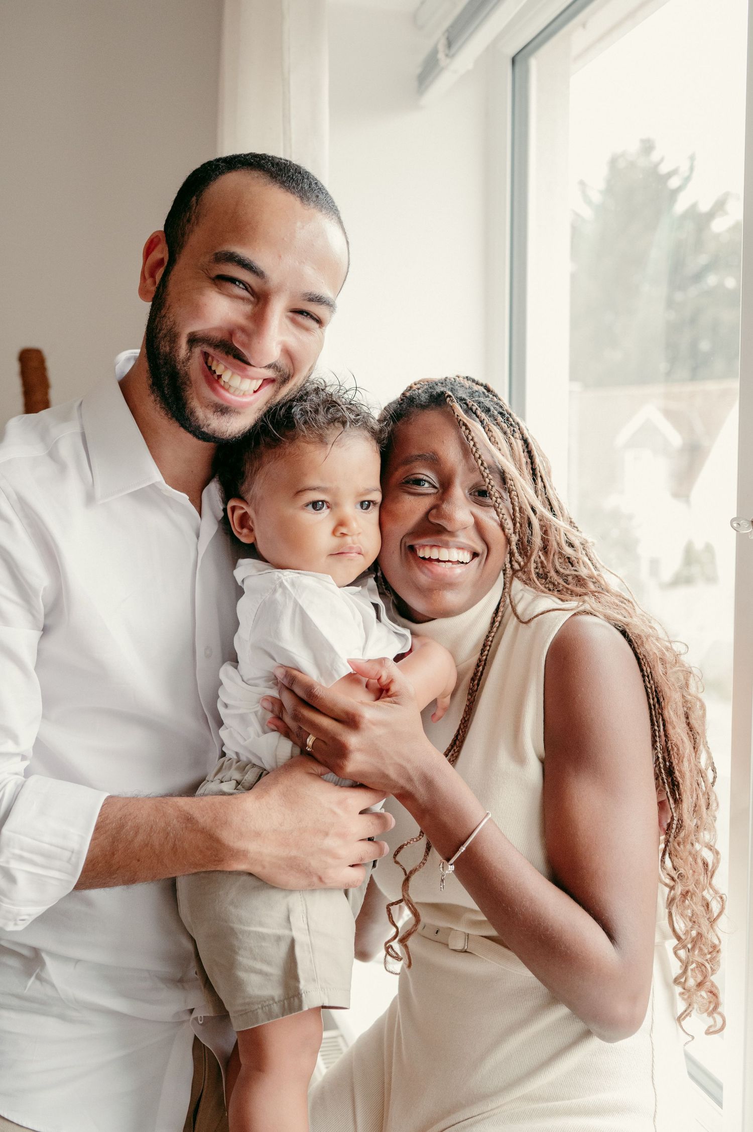 Family of three sharing joyful moment together by bright window.