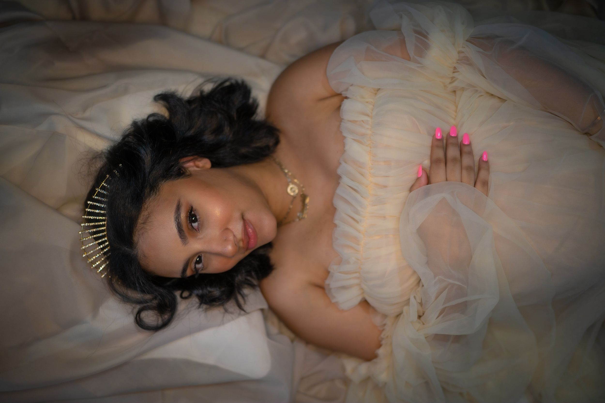 Person in an elegant white dress lying gracefully on a textured surface.