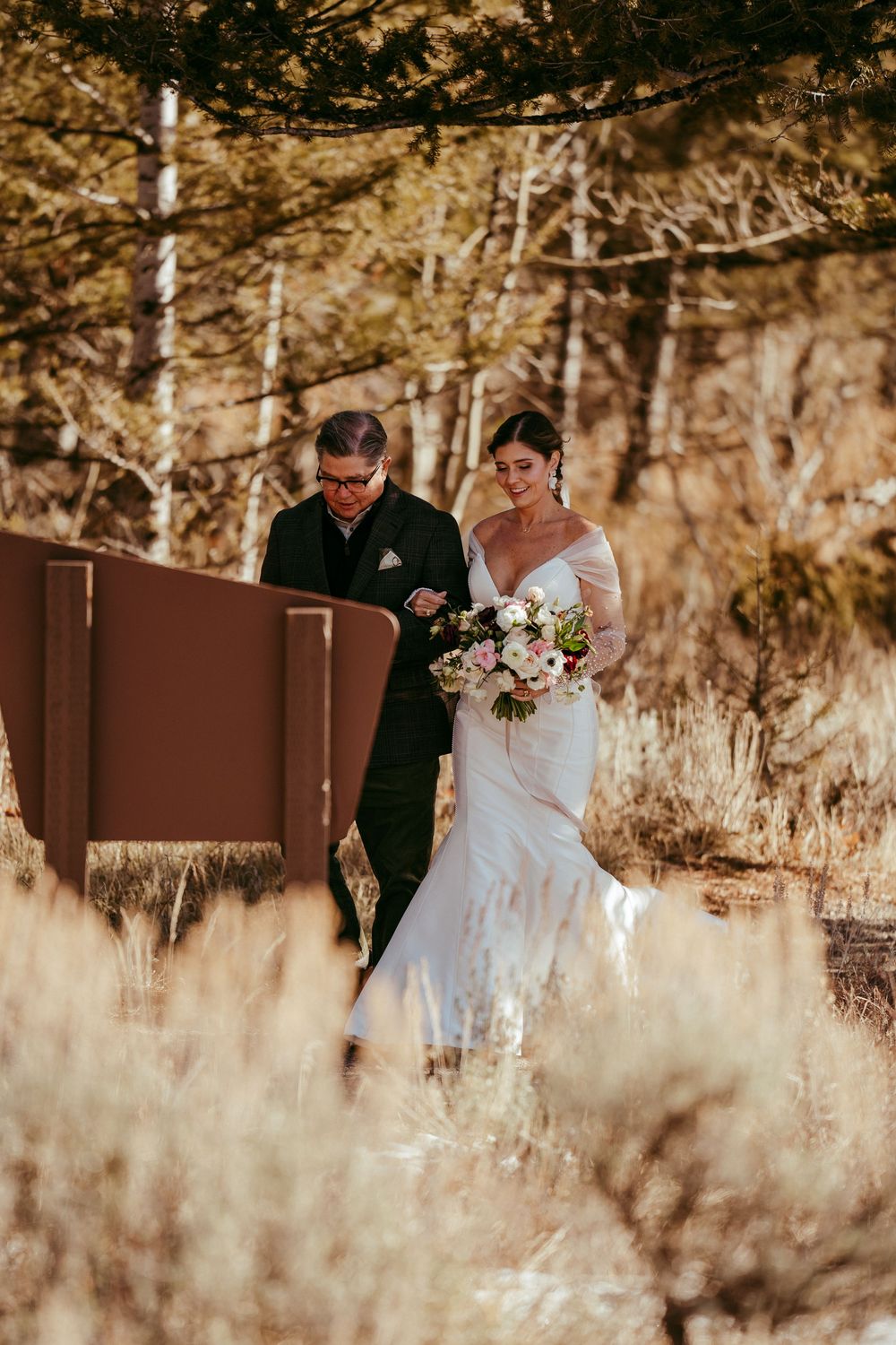 Romantic winter mountain wedding portrait of a bride and groom in a snowy landscape at golden hour.