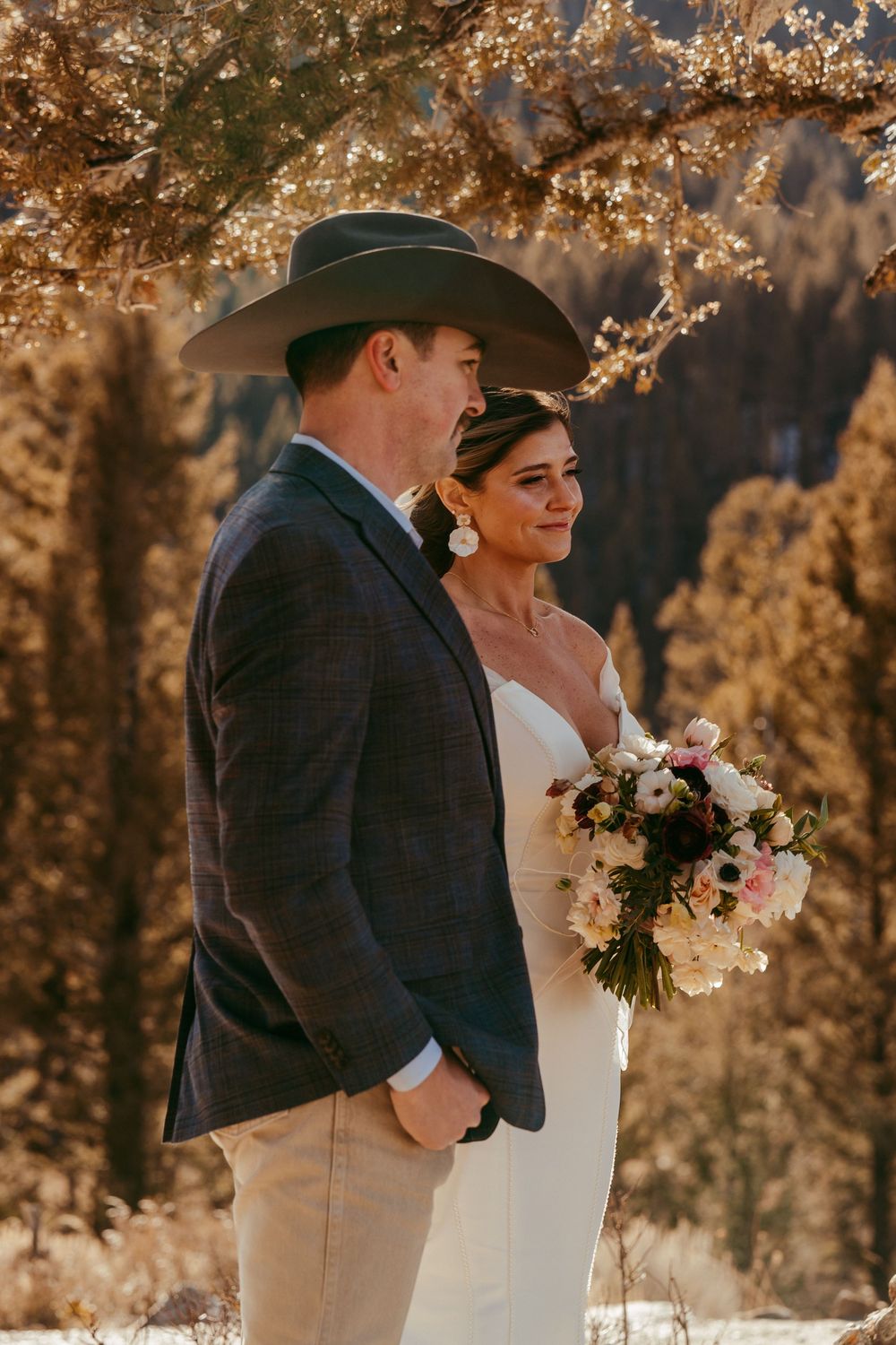 Romantic winter mountain wedding portrait of a bride and groom in a snowy landscape at golden hour.