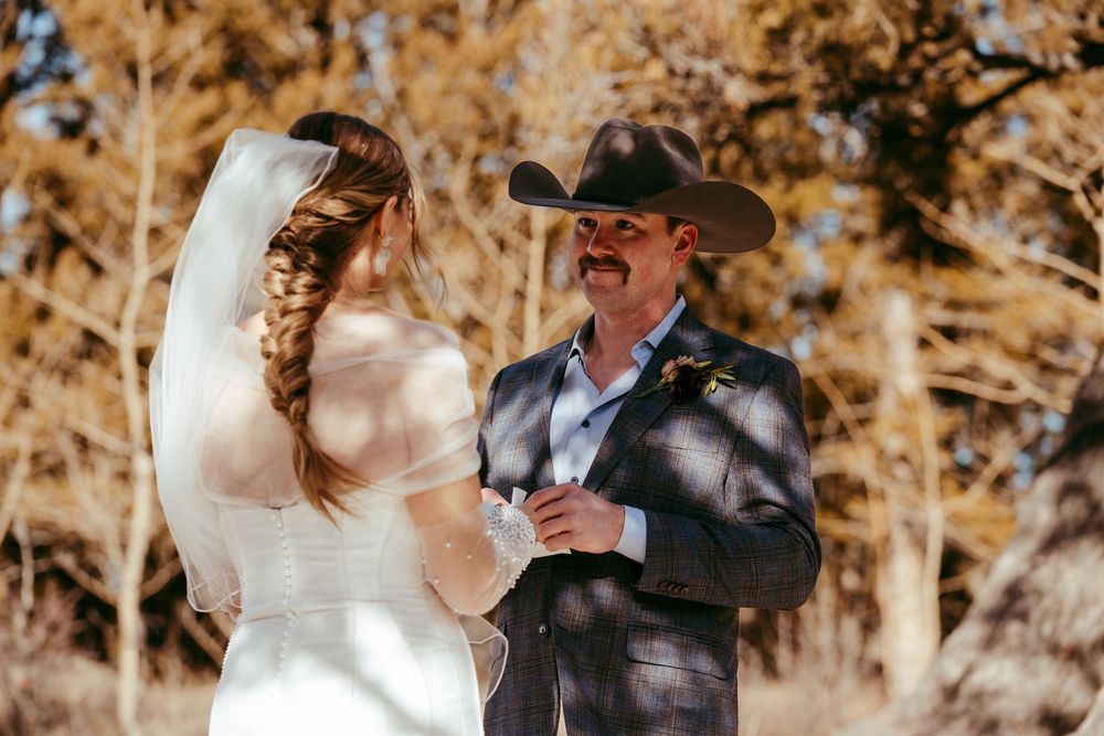 Romantic winter mountain wedding portrait of a bride and groom in a snowy landscape at golden hour.
