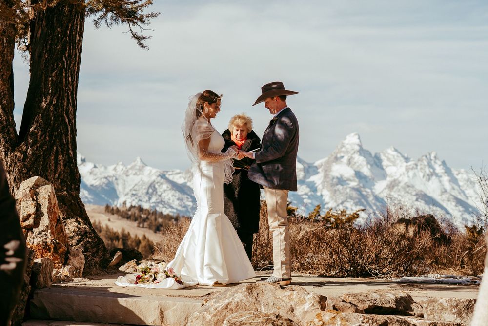 Romantic winter mountain wedding portrait of a bride and groom in a snowy landscape at golden hour.