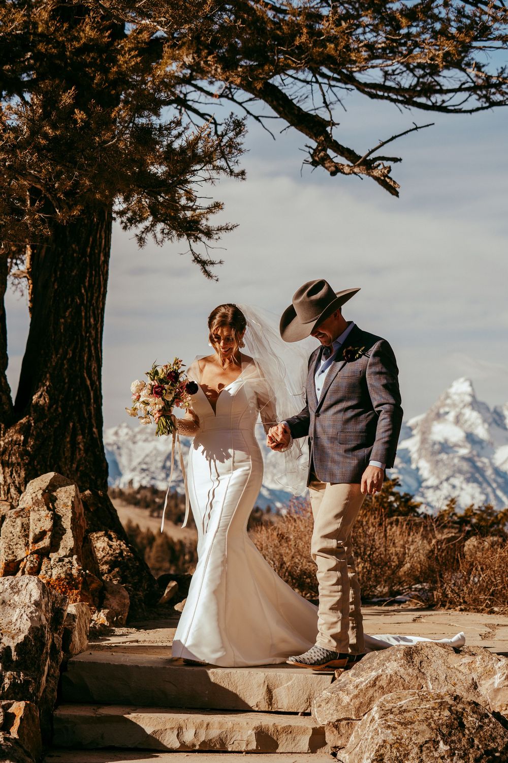 Romantic winter mountain wedding portrait of a bride and groom in a snowy landscape at golden hour.