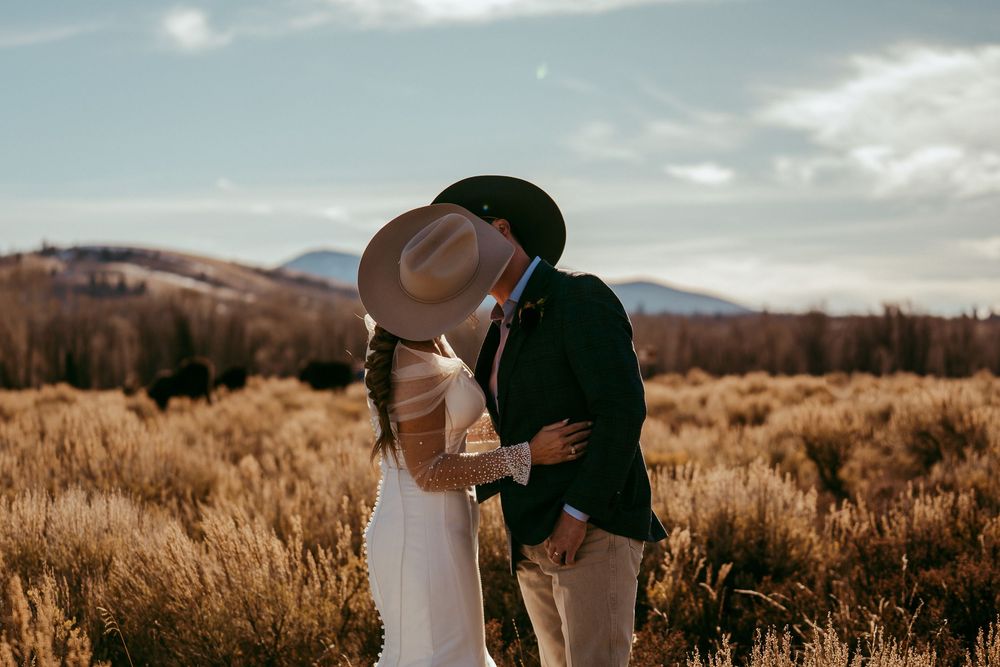 Romantic winter mountain wedding portrait of a bride and groom in a snowy landscape at golden hour.