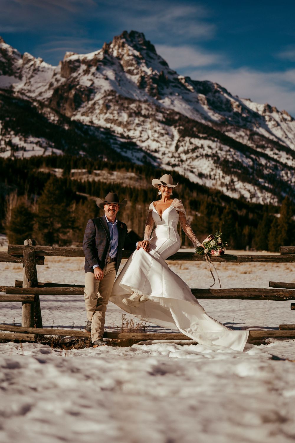 Romantic winter mountain wedding portrait of a bride and groom in a snowy landscape at golden hour.