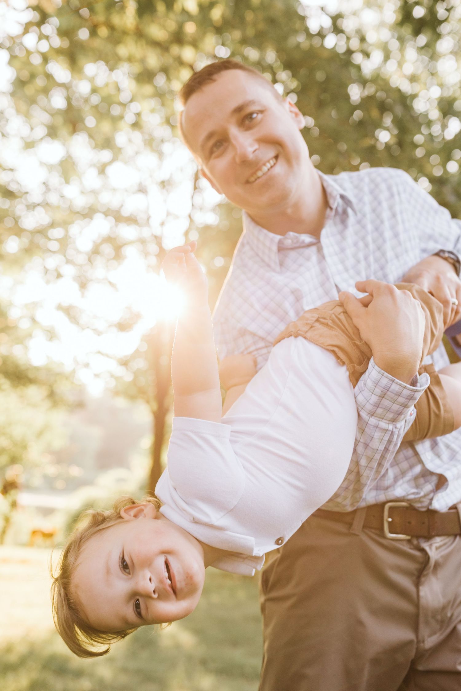 Playful outdoor portrait with sunlit background showing joyful interaction.