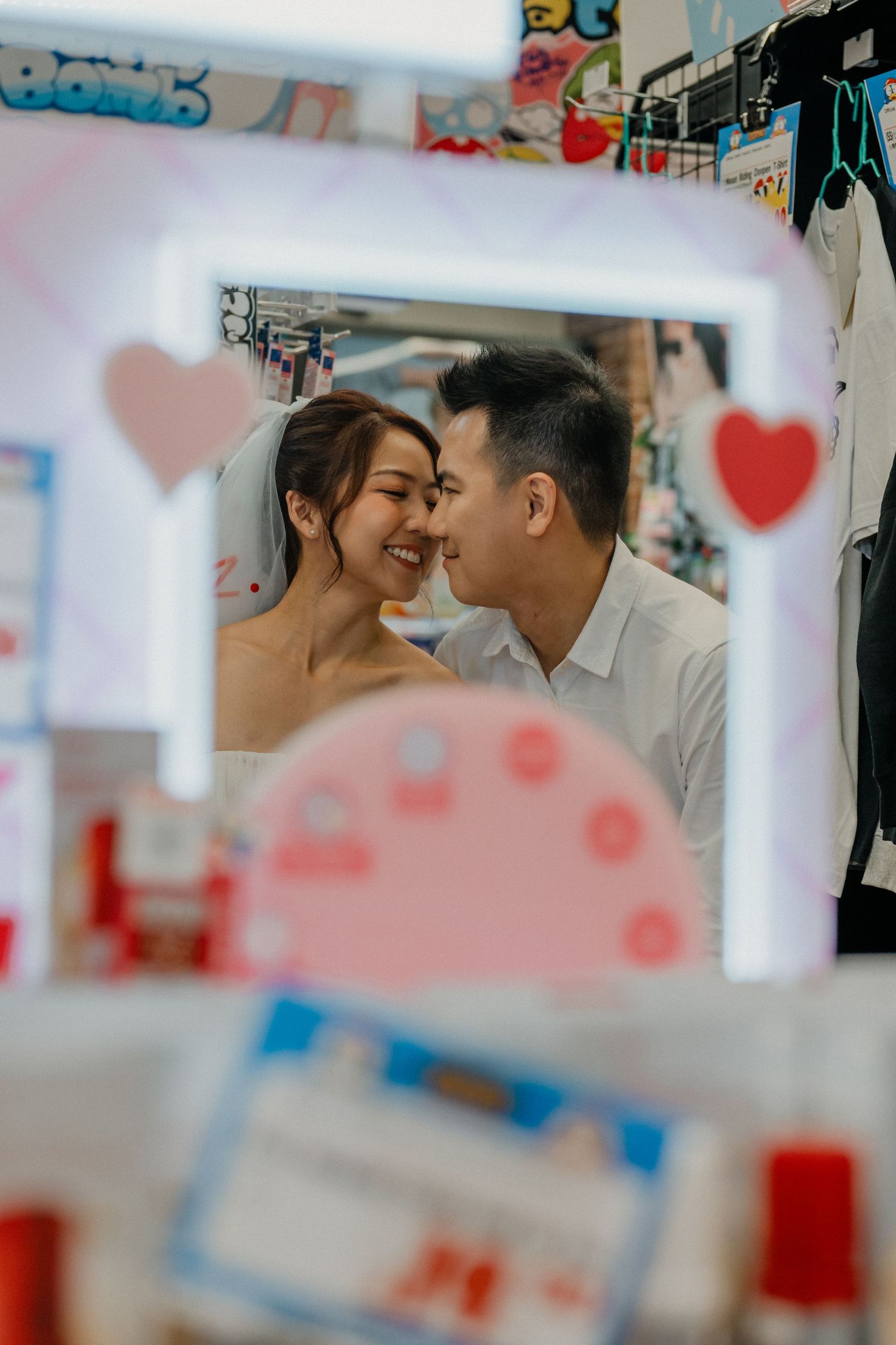 A romantic photoshoot between shelves with blurred foreground elements.
