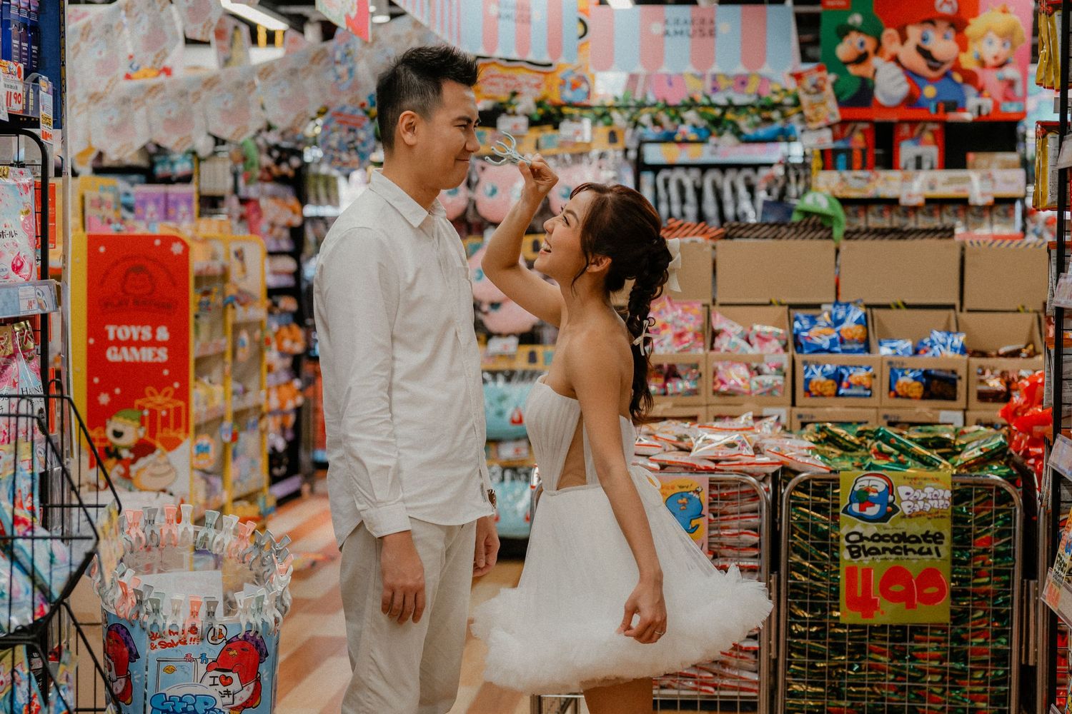 Candid moment between a couple dancing in a grocery store surrounded by shelves of snacks.