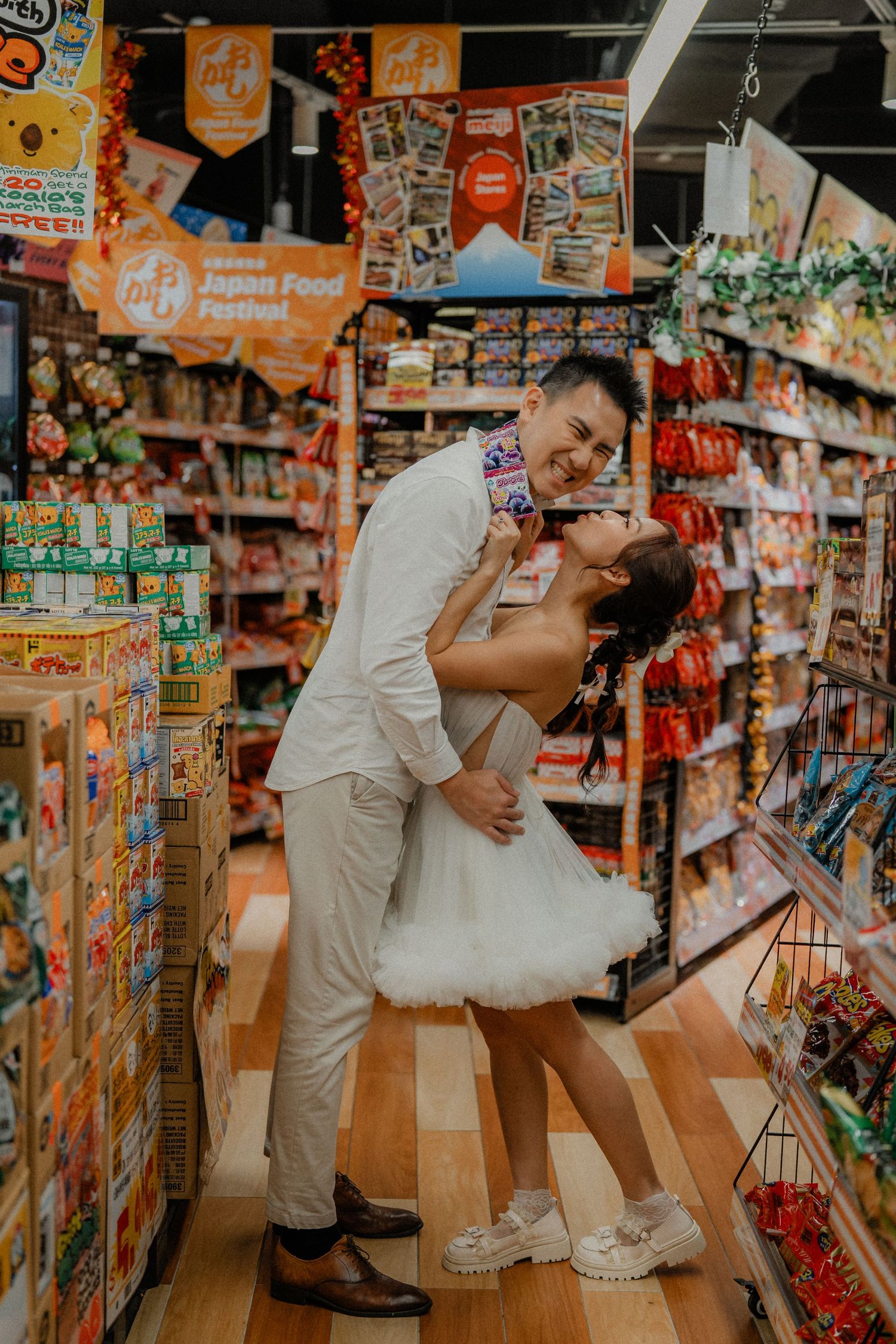 Dancing duo creates artistic poses among snack shelves in supermarket.