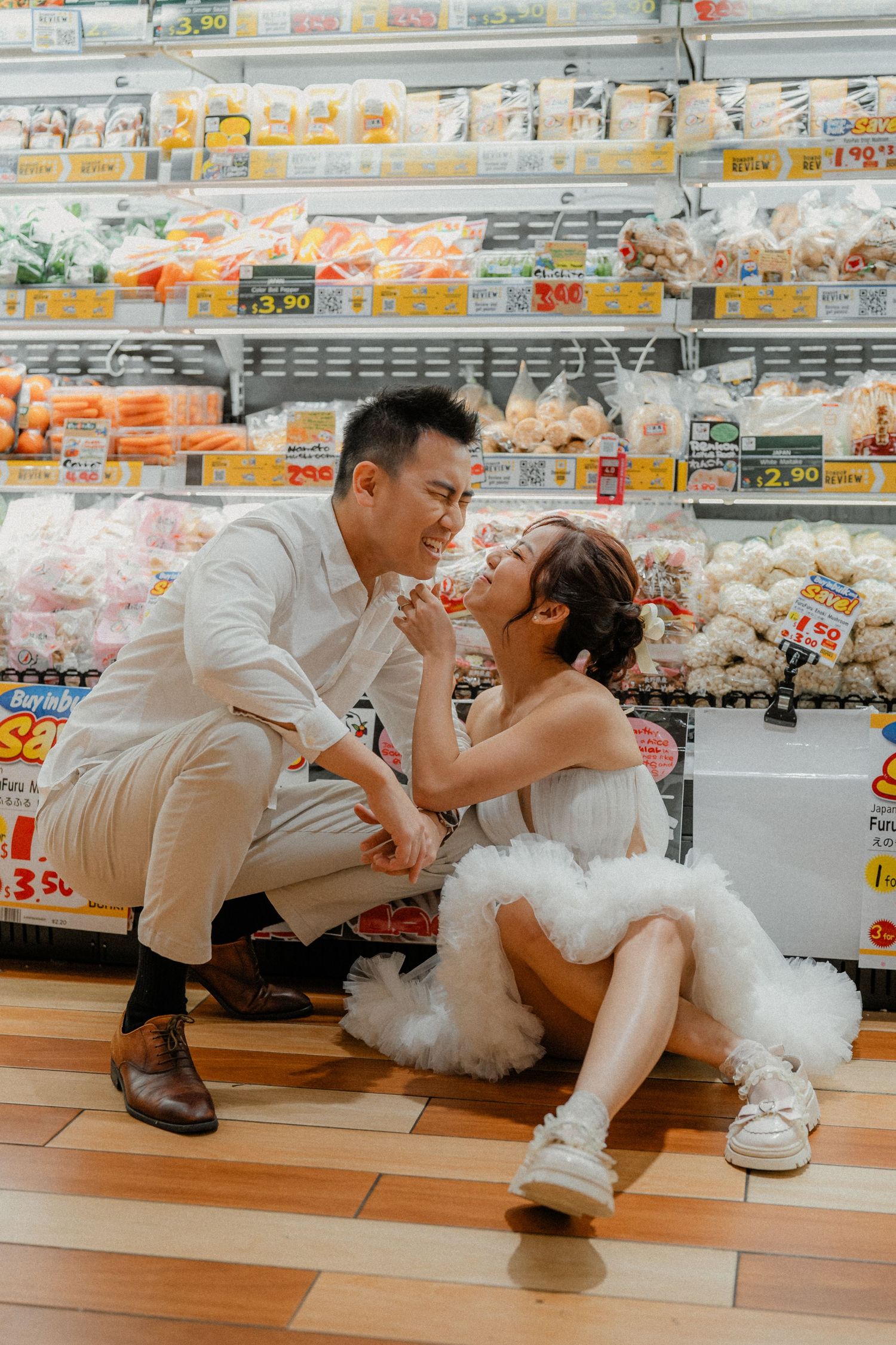 Romantic couple in white outfits sharing a sweet moment on grocery store floor.