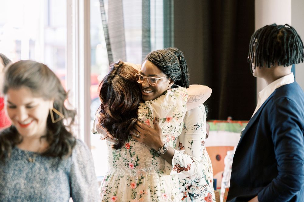 Joyful embrace at a celebration with guests in formal attire.