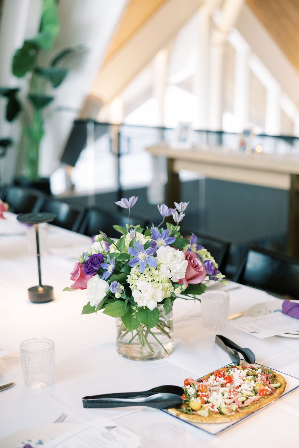 Elegant table settings at an event feature delicate floral centerpieces and plated appetizers on a white tablecloth.