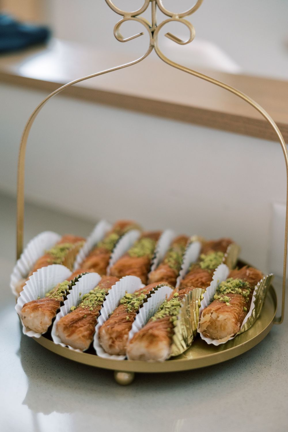 Row of elegant mini sandwiches with garnish displayed on a gold platter with a decorative handle.