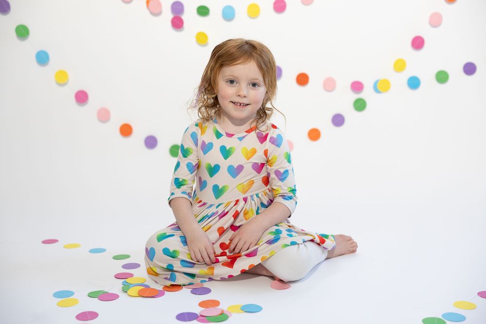 Colorful polka dot dress and decor create a cheerful studio photography setting with confetti on white background.