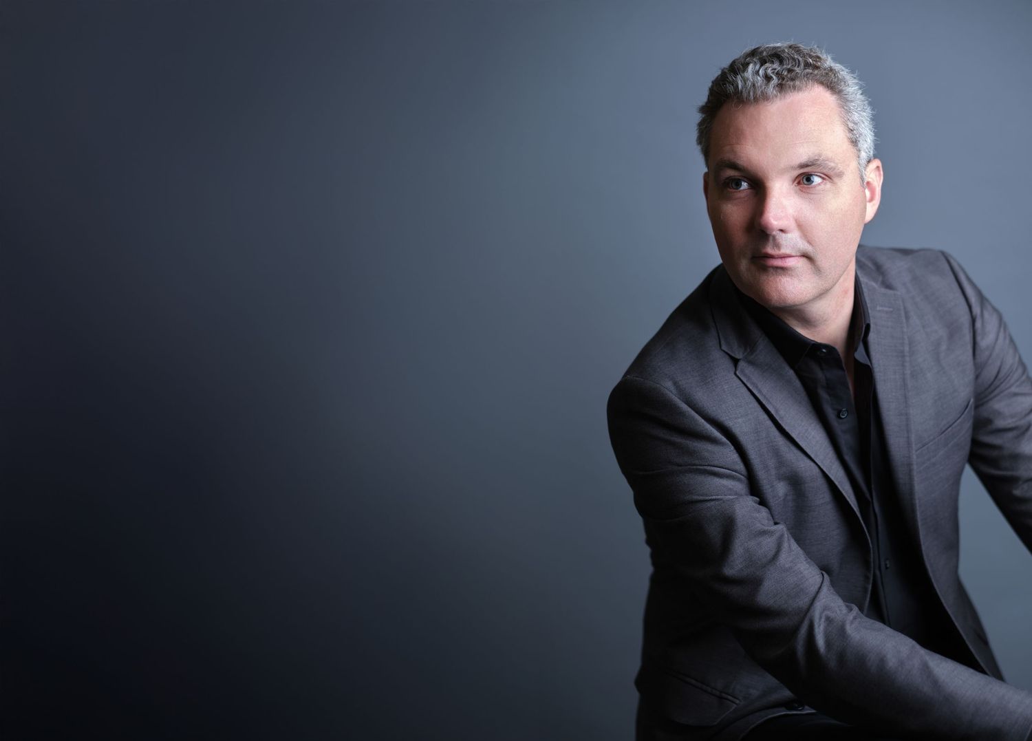 Professional headshot with expressive lighting and subject looking into negative space.