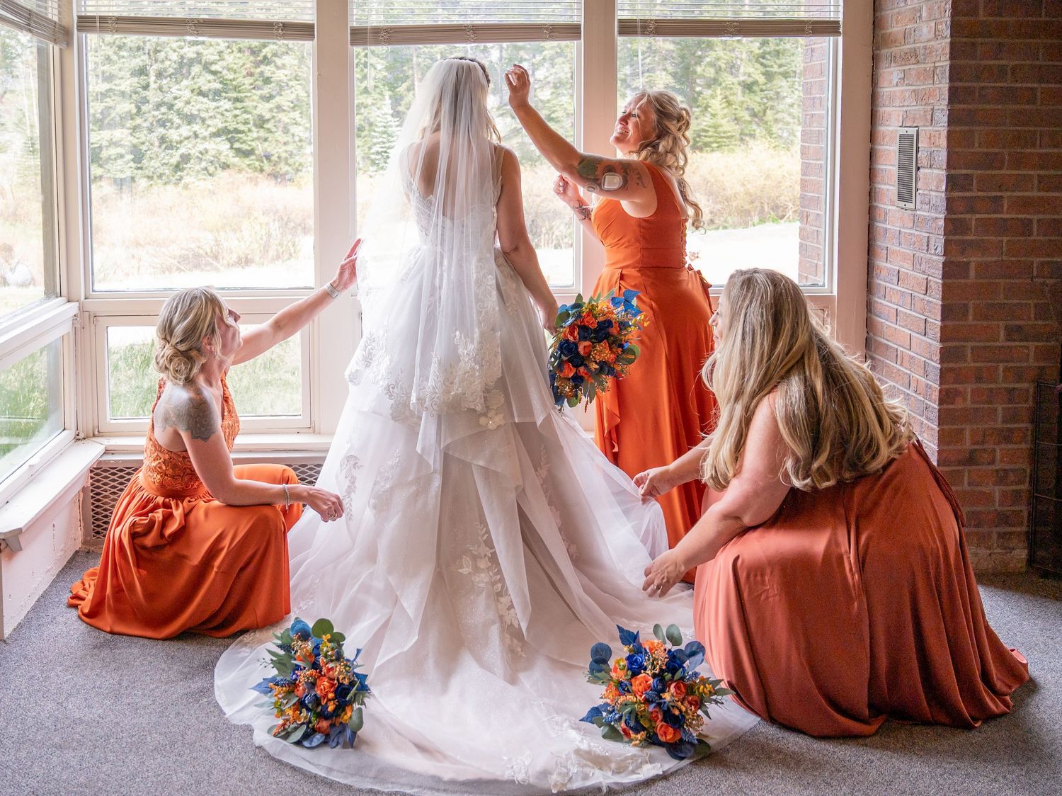 A wedding photo collage showing bridesmaids in coral dresses sitting by window with bride's white gown and colorful bouquets.