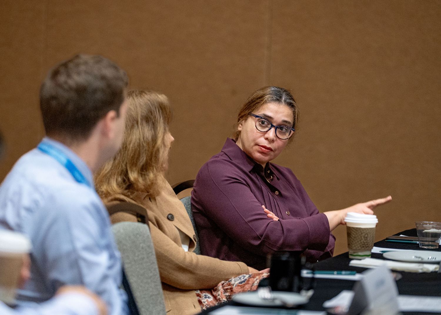 Conference attendees engaged in discussion at meeting table.