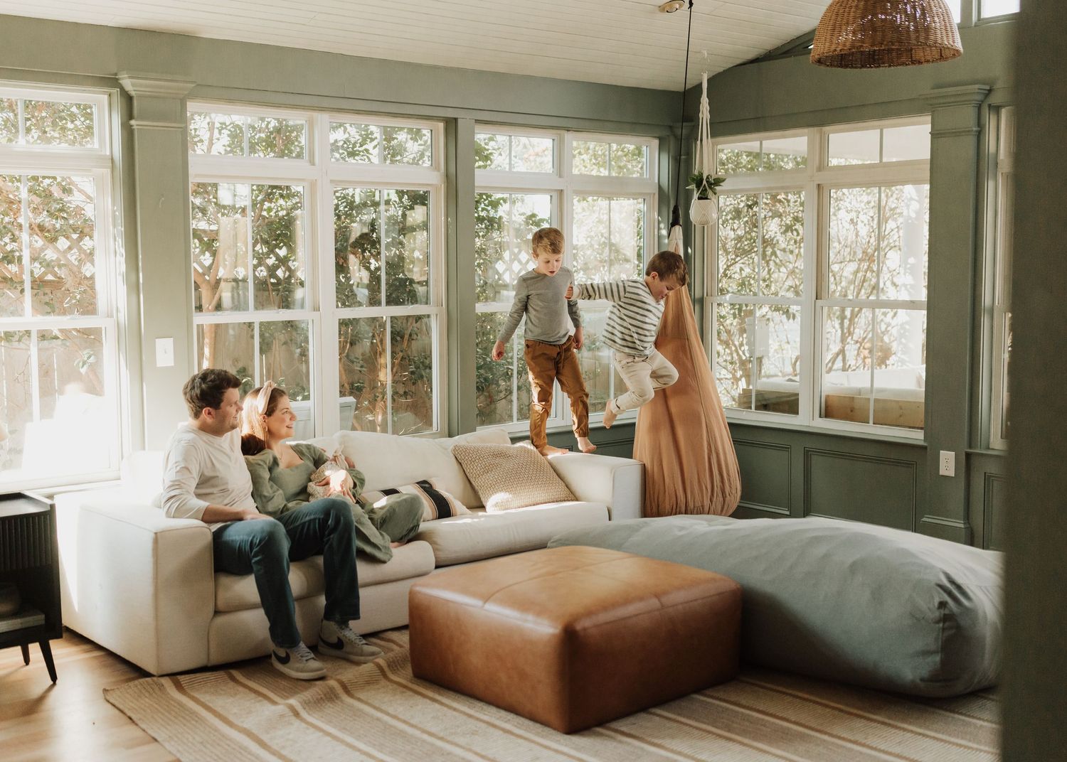 A contemporary living room with panoramic windows features white sofa seating and warm wood accents in natural lighting.