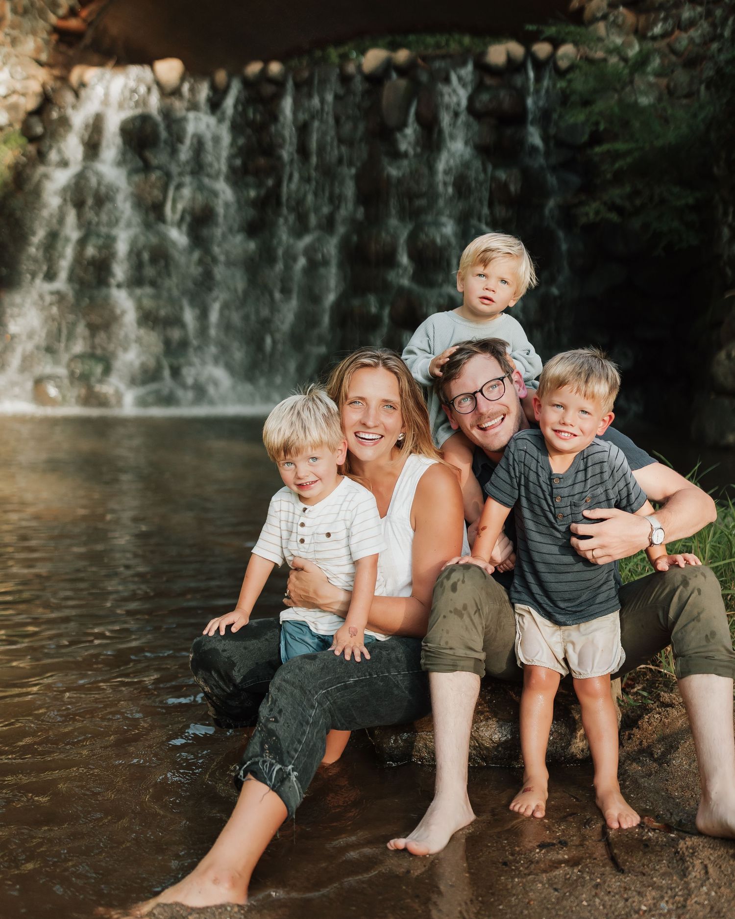 A family shares joyful moments by a scenic waterfall backdrop across a series of candid photos.