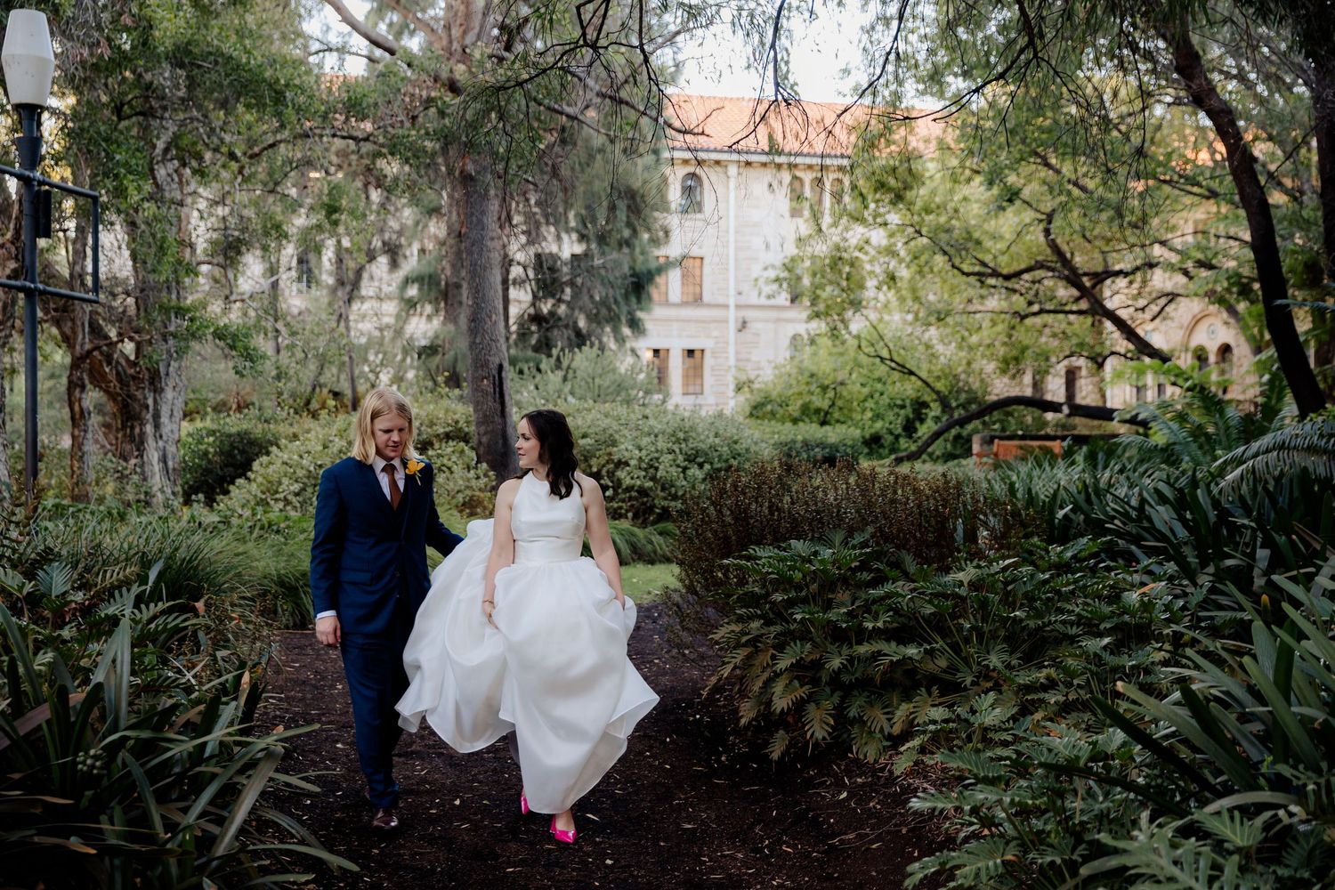 Joyful wedding couple shares intimate moments together in a lush garden setting with spring blooms and greenery.