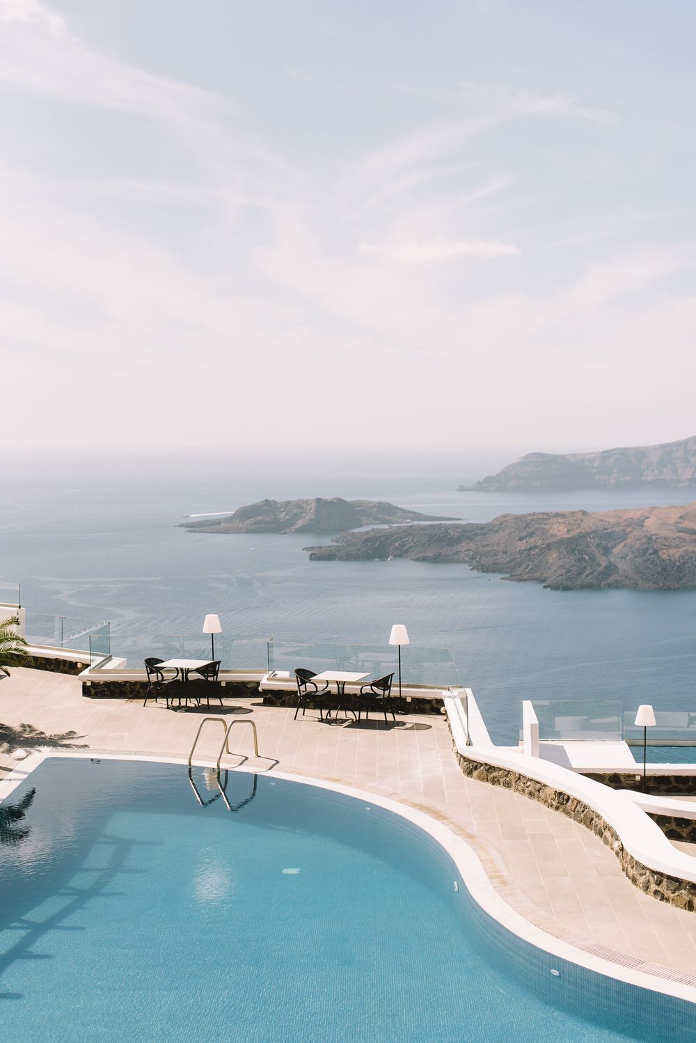 Stunning infinity pool overlooking the blue Mediterranean Sea and rugged coastal cliffs of Santorini, Greece.