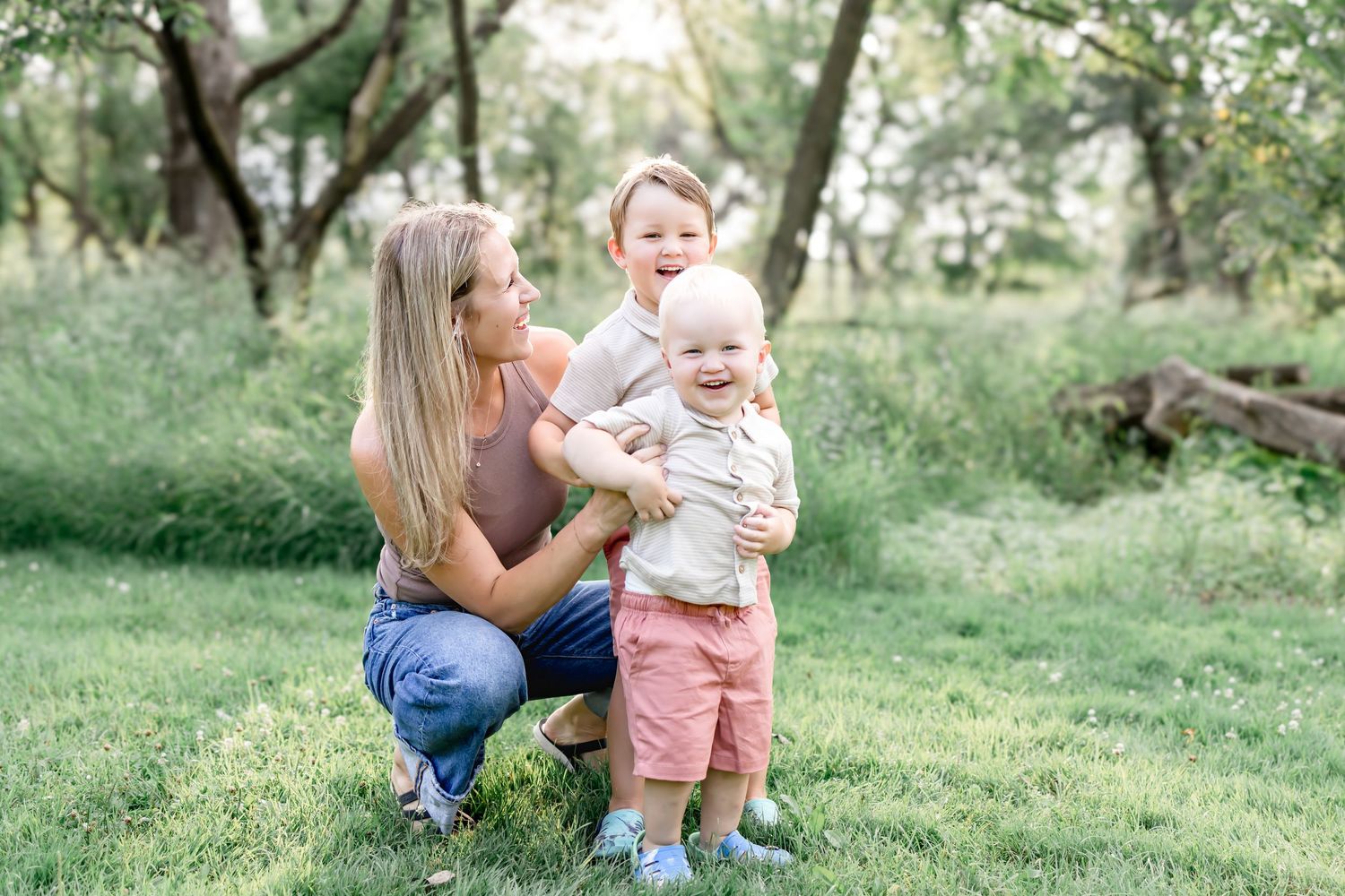 Mother and baby playing together outdoors in a sunny green garden setting.