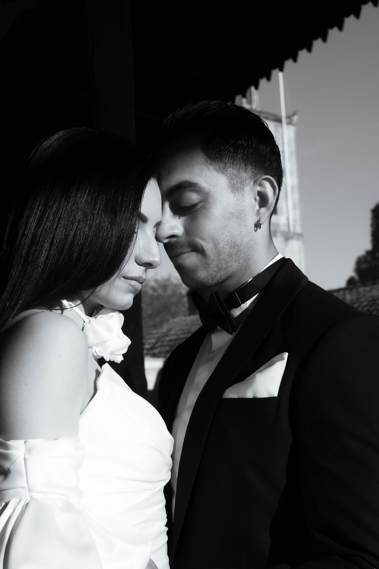 A romantic black and white wedding portrait of a couple in formal attire sharing an intimate moment together.