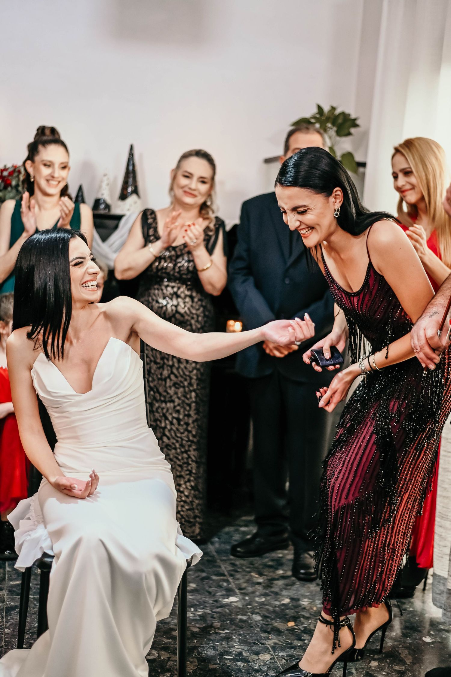 People dancing and having fun at a wedding reception with guests in black, white, and burgundy attire.