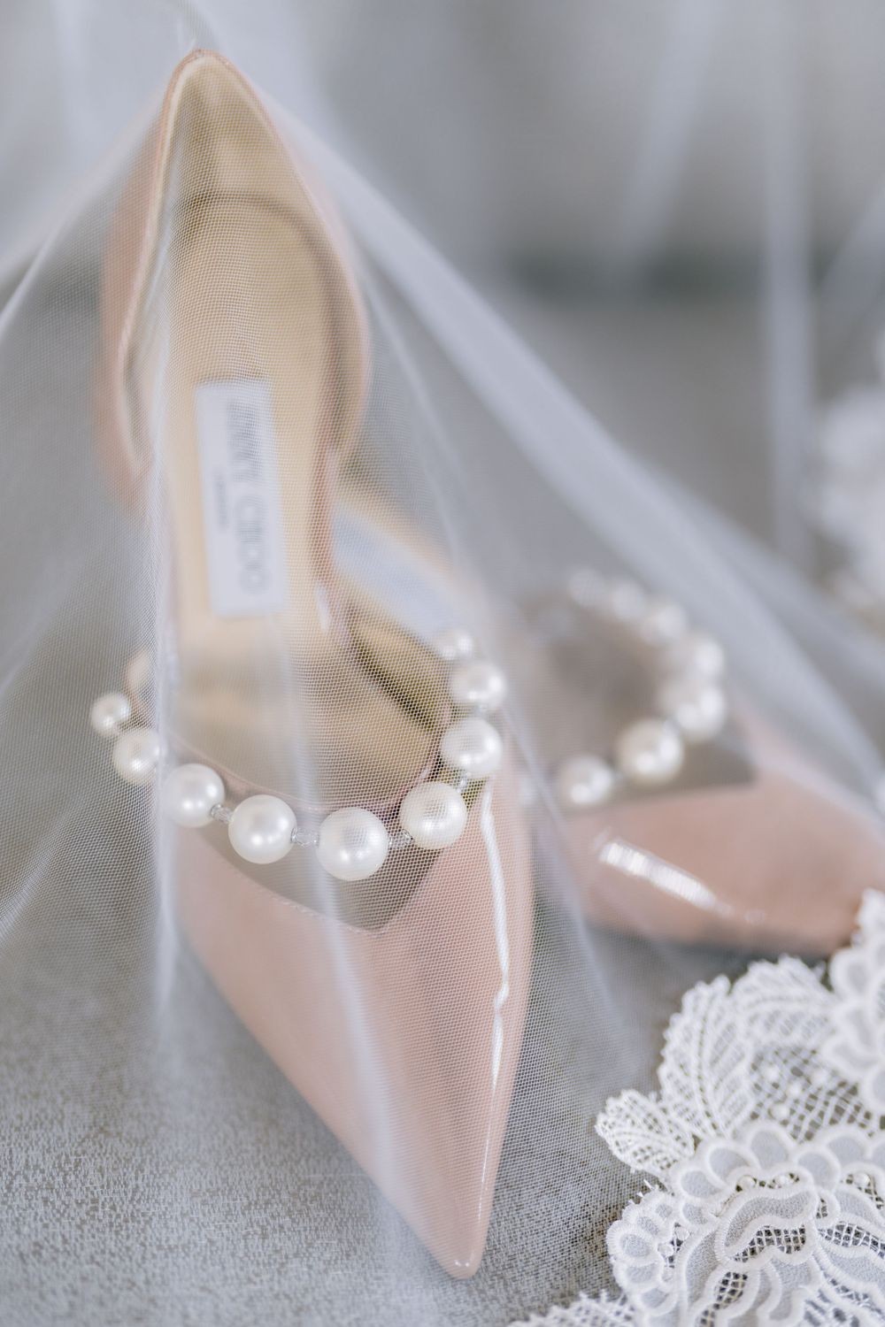 Elegant nude patent leather wedding shoes with pearl details and delicate white lace accents.
