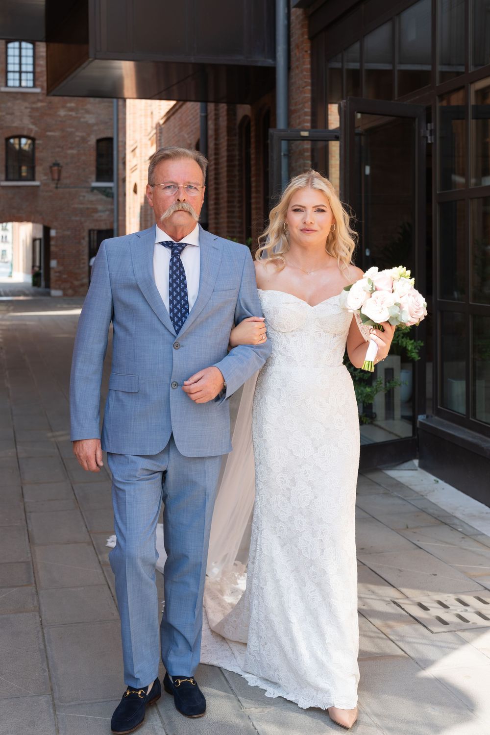 A wedding party walking along a modern brick building exterior. Photoshoot by Venice Photographer Alina Indi
