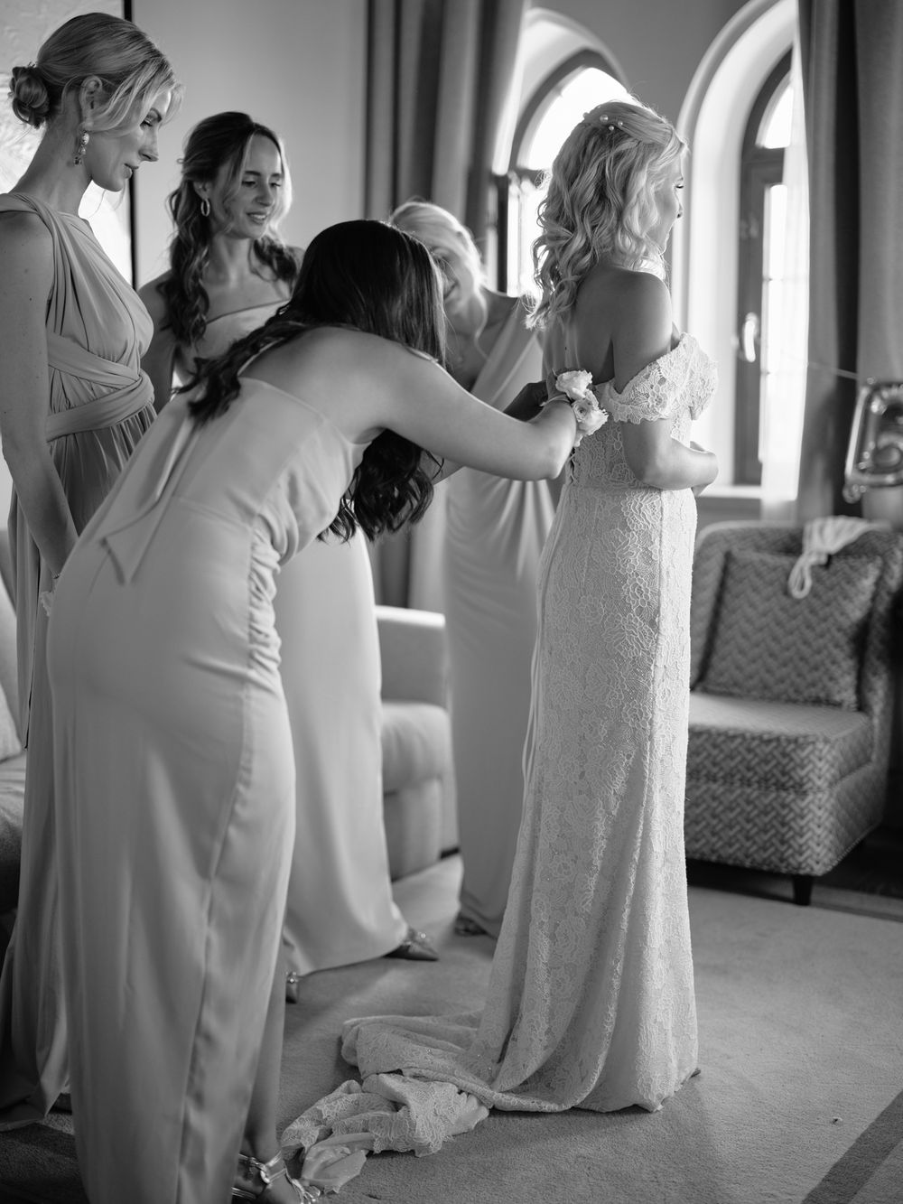 Black and white photos of bridesmaids helping with wedding dress preparations. Photoshoot by Venice Photographer Alina Indi