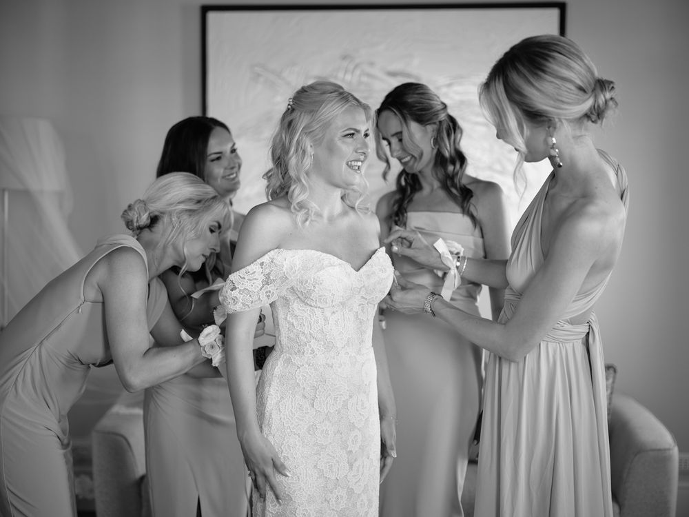 Bridesmaids in pink dresses assist with final wedding dress adjustments.Photoshoot by Venice Photographer Alina Indi